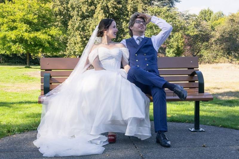 Newlyweds laughing together on a park bench