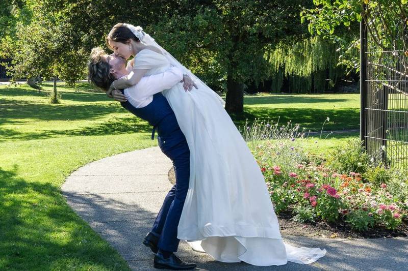 Groom lifting the bride into a kiss on a garden path