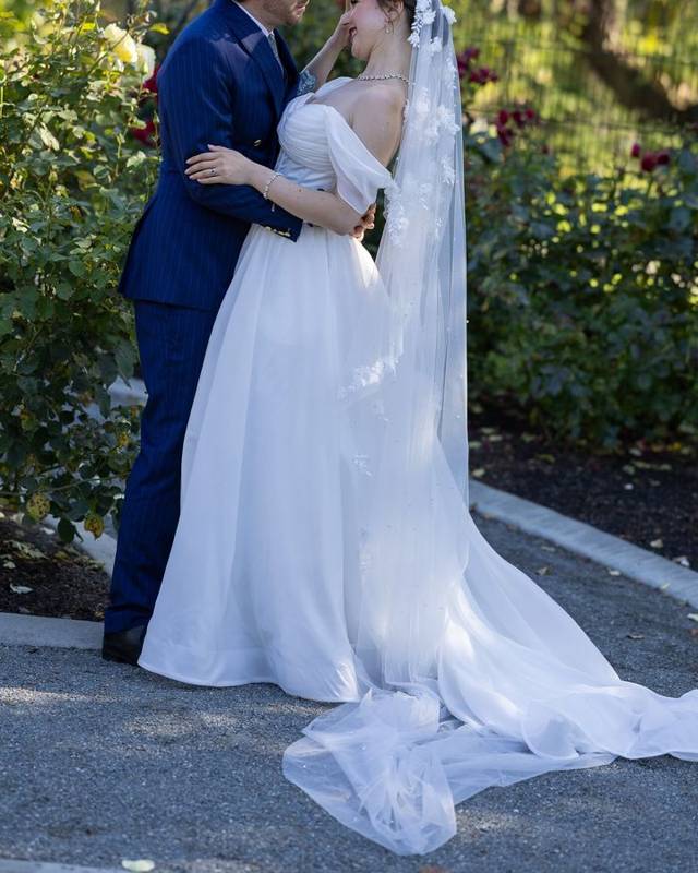 Couple embracing on a garden path, her veil and train trailing behind