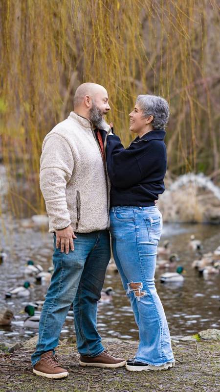 Couple smiling at each other at the edge of a pond