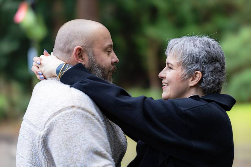 She wraps her arms around his neck, smiling