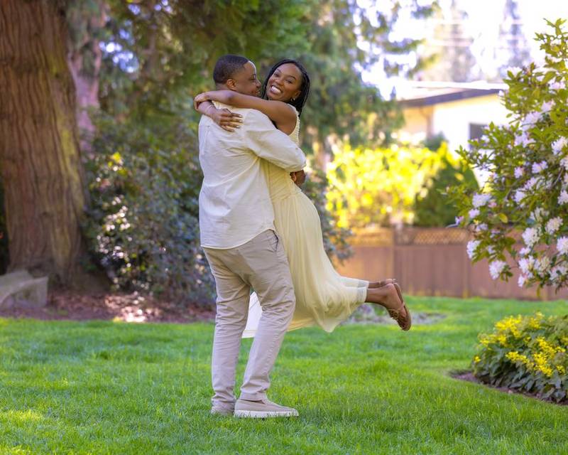 He lifts her into a hug on a green lawn