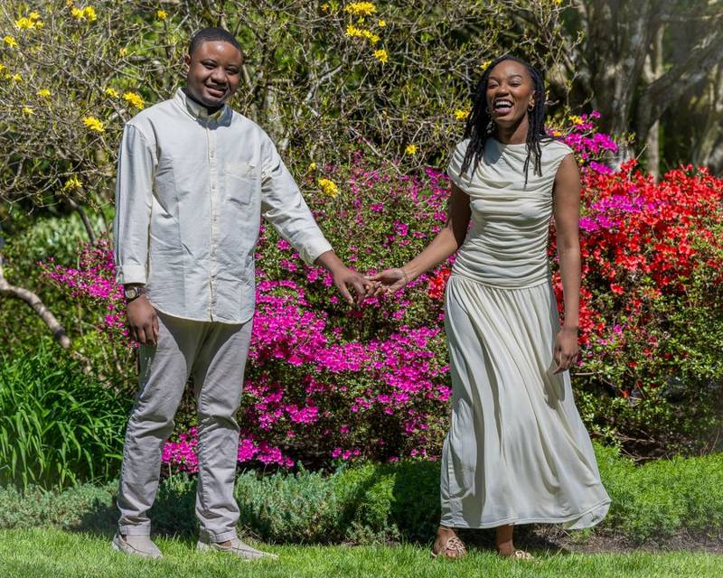 Couple holding hands in front of pink and red azaleas