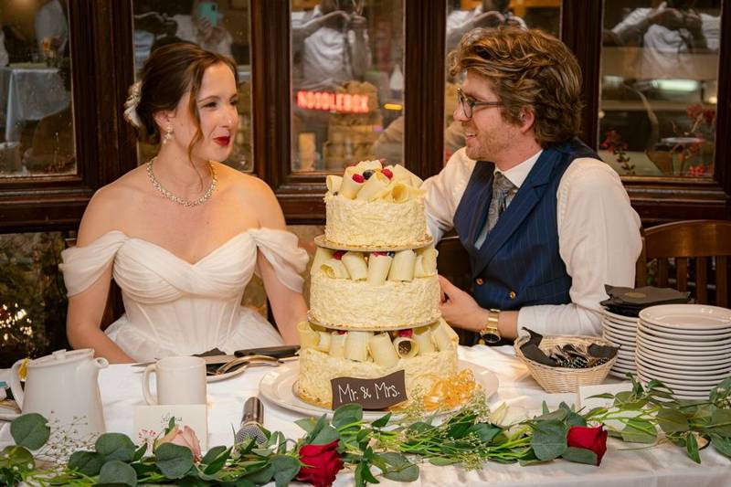 Bride and groom at the head table behind their tiered cake