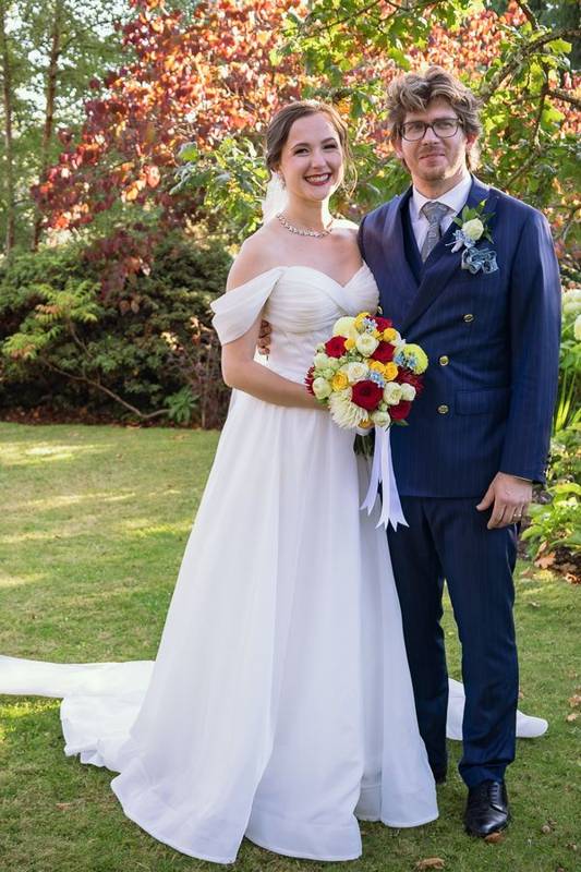 Bride and groom smiling at the camera in an autumn garden